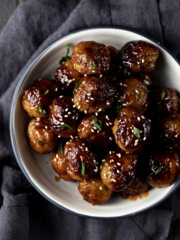 glazed meatballs with sesame seeds and green garnish