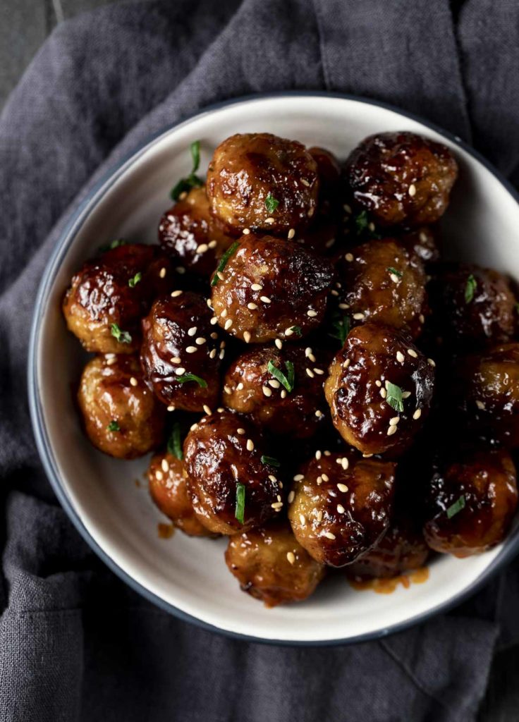 glazed meatballs with sesame seeds and green garnish