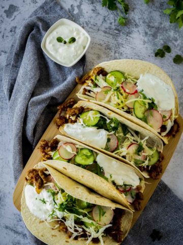 Overhead view of spicy lamb tacos on a serving board.