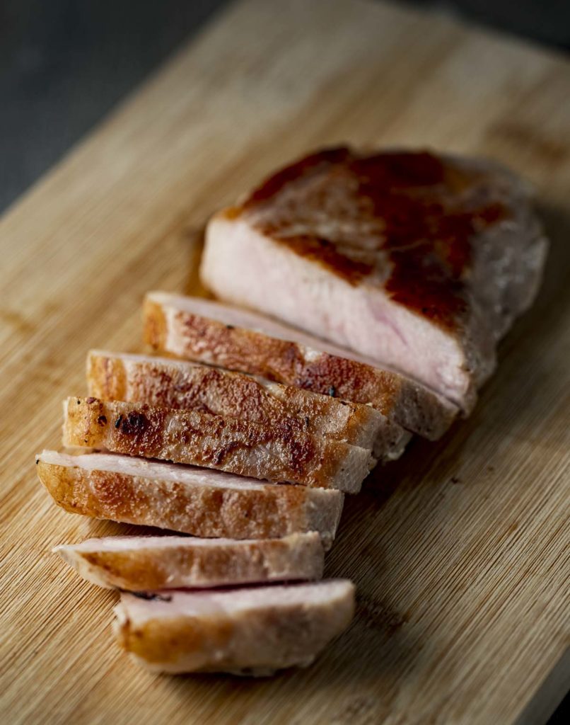 sliced pork fanned across a cutting board