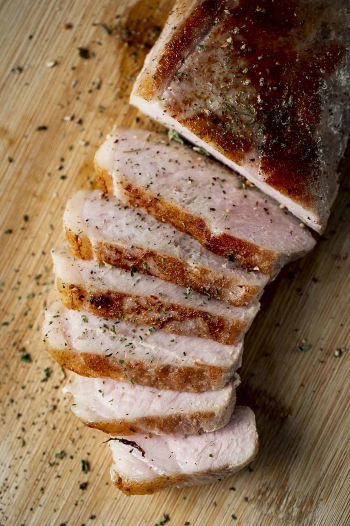sliced pork on a surface with cracked pepper