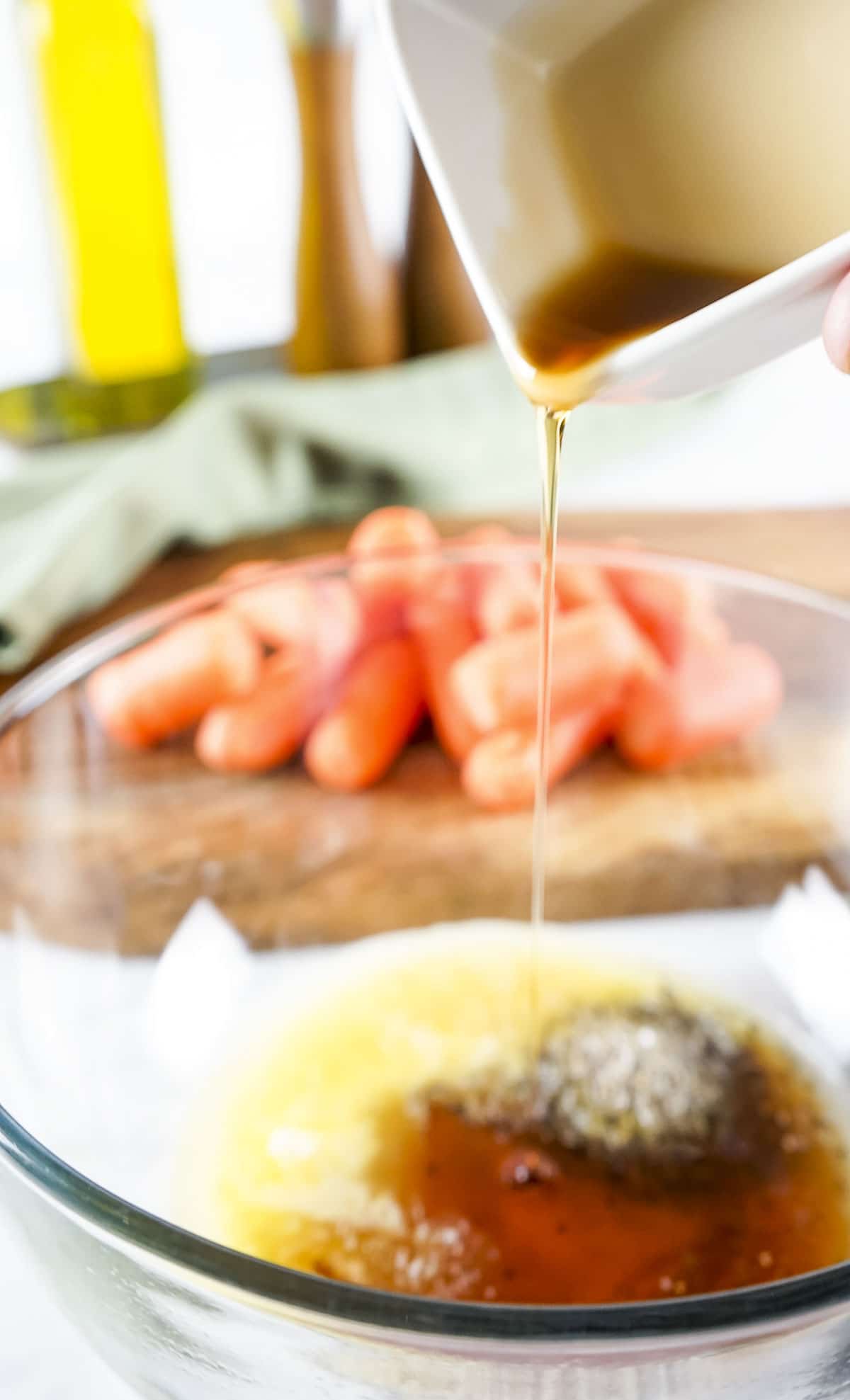 Maple syrup being poured into a bowl of melted butter and seasonings.
