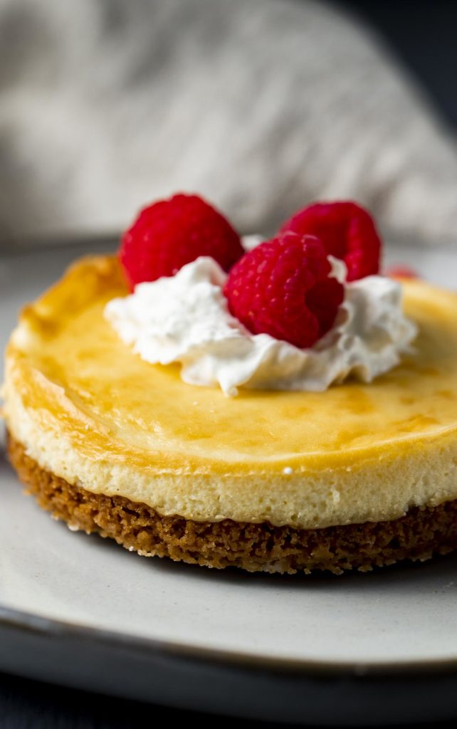 Air fryer cheesecake with whipped cream and raspberries.