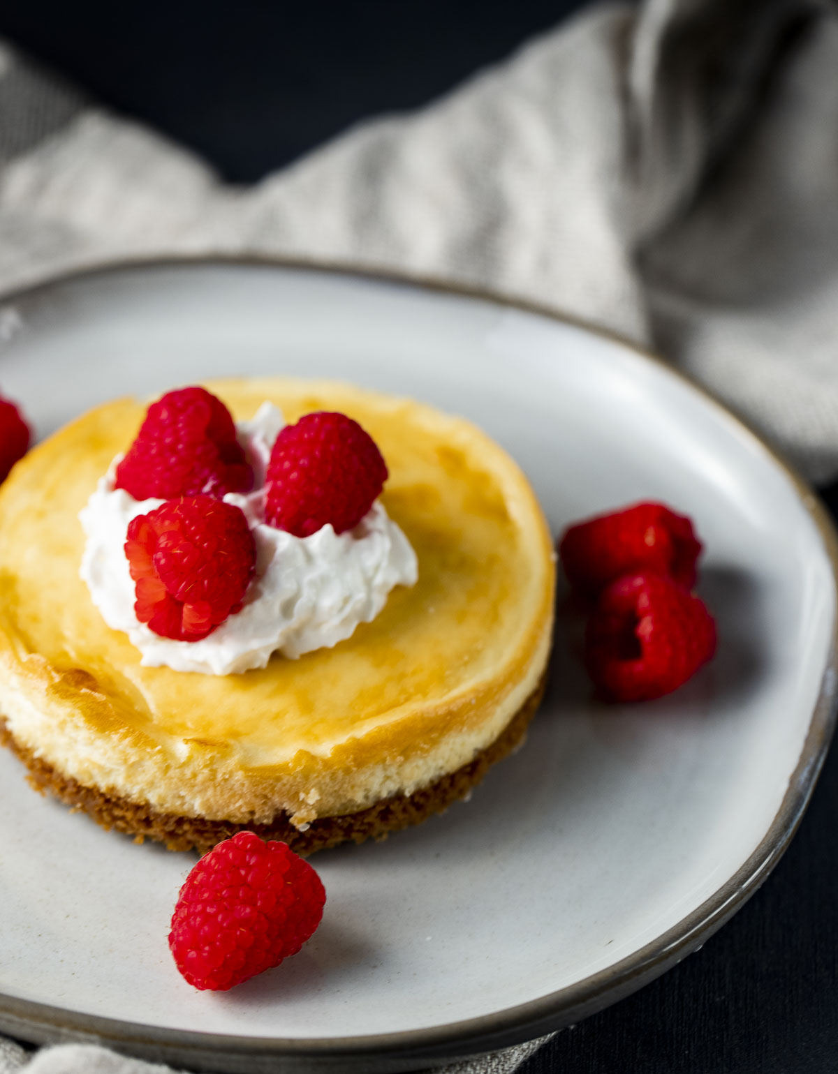 Air fryer cheesecake with whipped cream and raspberries.