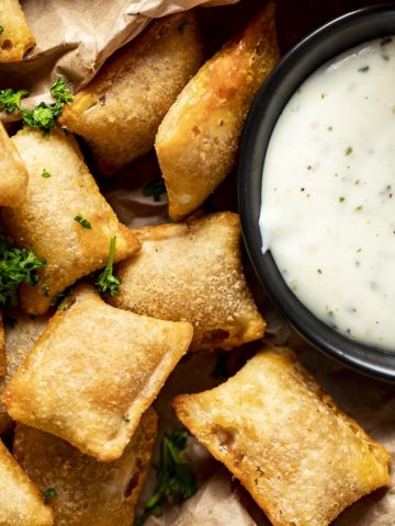 Overhead view of air fryer pizza rolls beside a ranch dipping sauce.