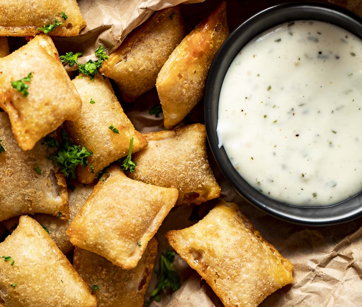 Overhead view of air fryer pizza rolls beside a ranch dipping sauce.