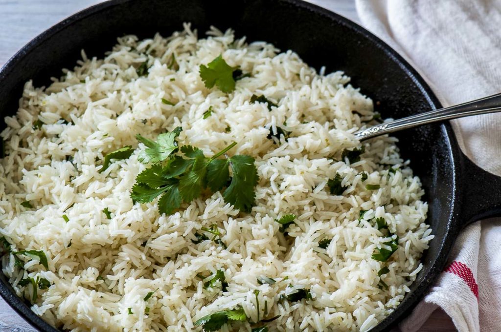 White rice with lime and cilantro in a skillet.