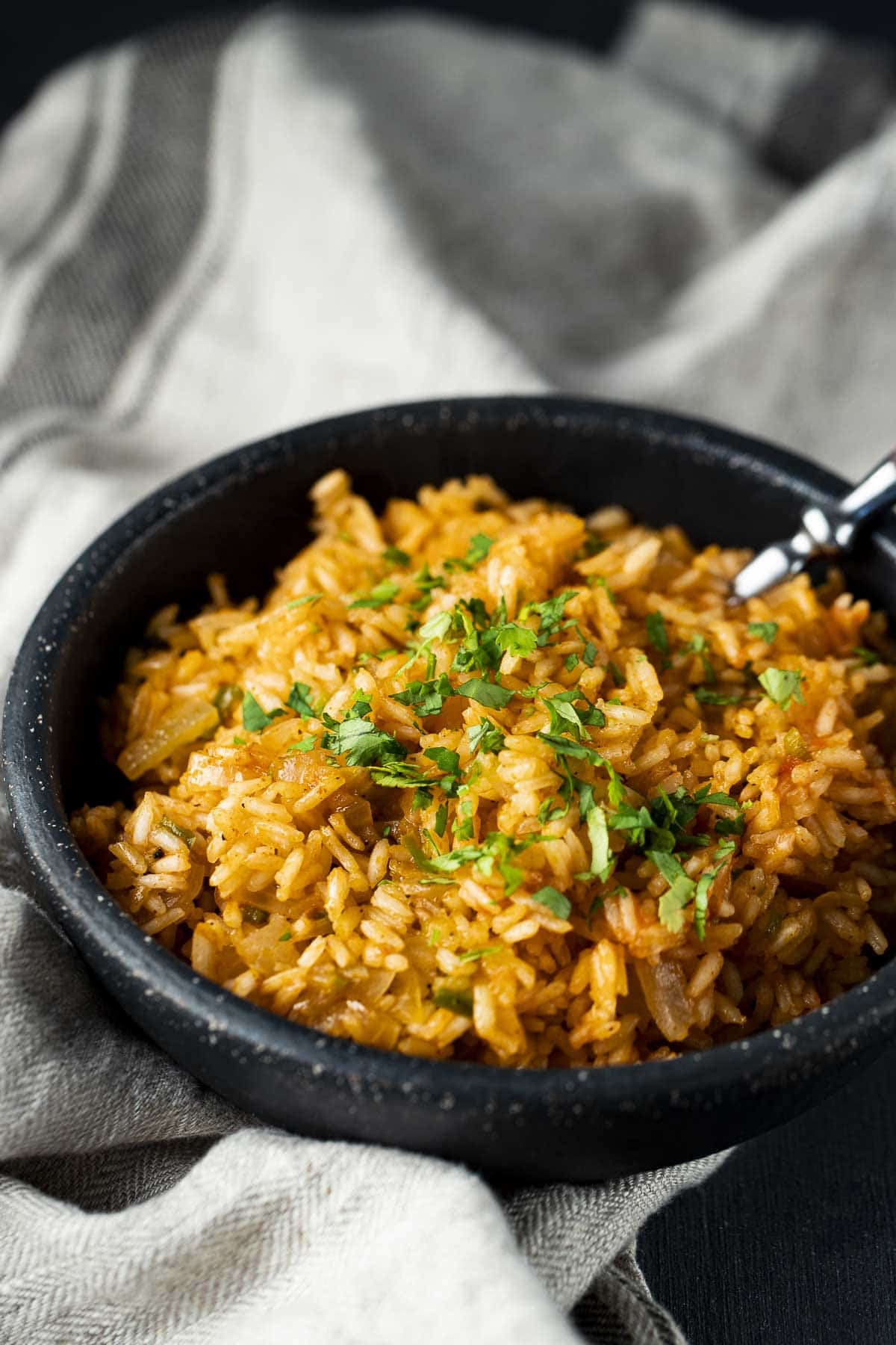 A bowl of Spanish rice with a spoon inserted.