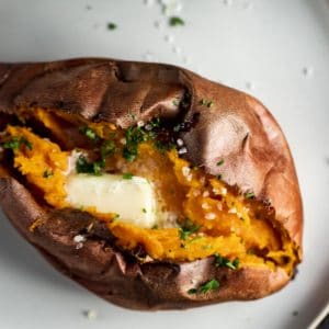 An air fryer sweet potato on a plate with melting butter on top.