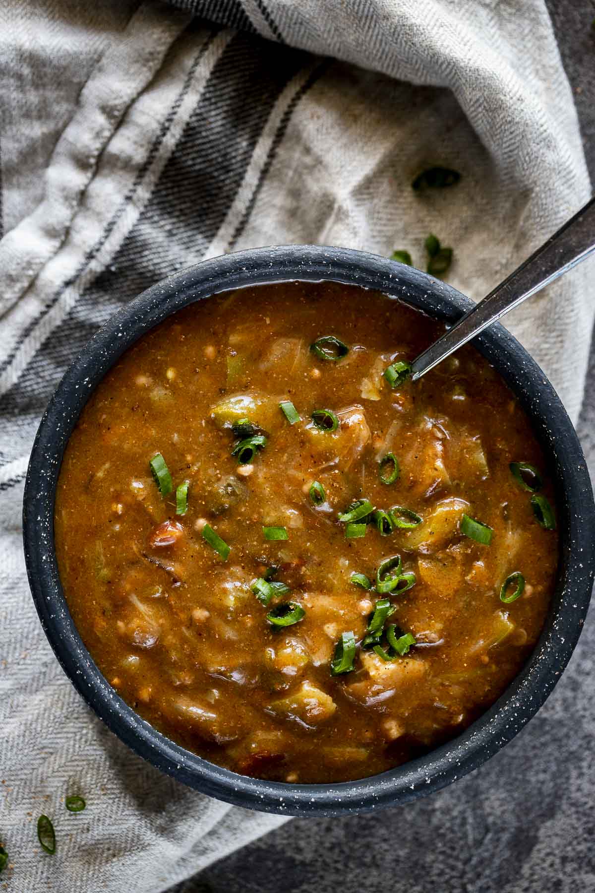 Instant Pot chicken and sausage gumbo in a dark bowl with a spoon.