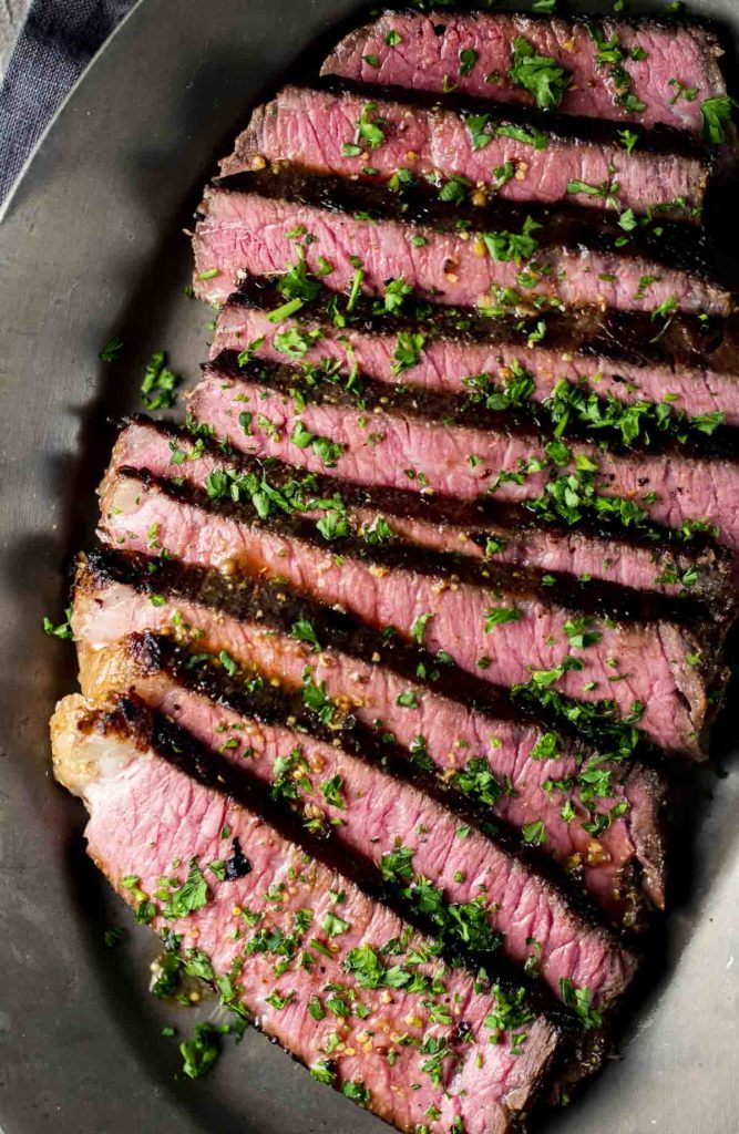 Overhead of London broil sliced in a frying pan.