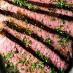 Close up of a London broil sliced and garnished with herbs.