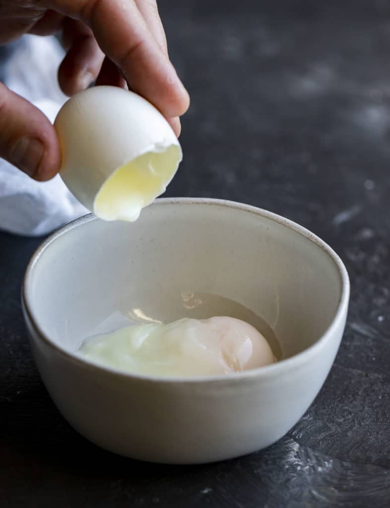 Pouring the egg from the shell into a bowl.