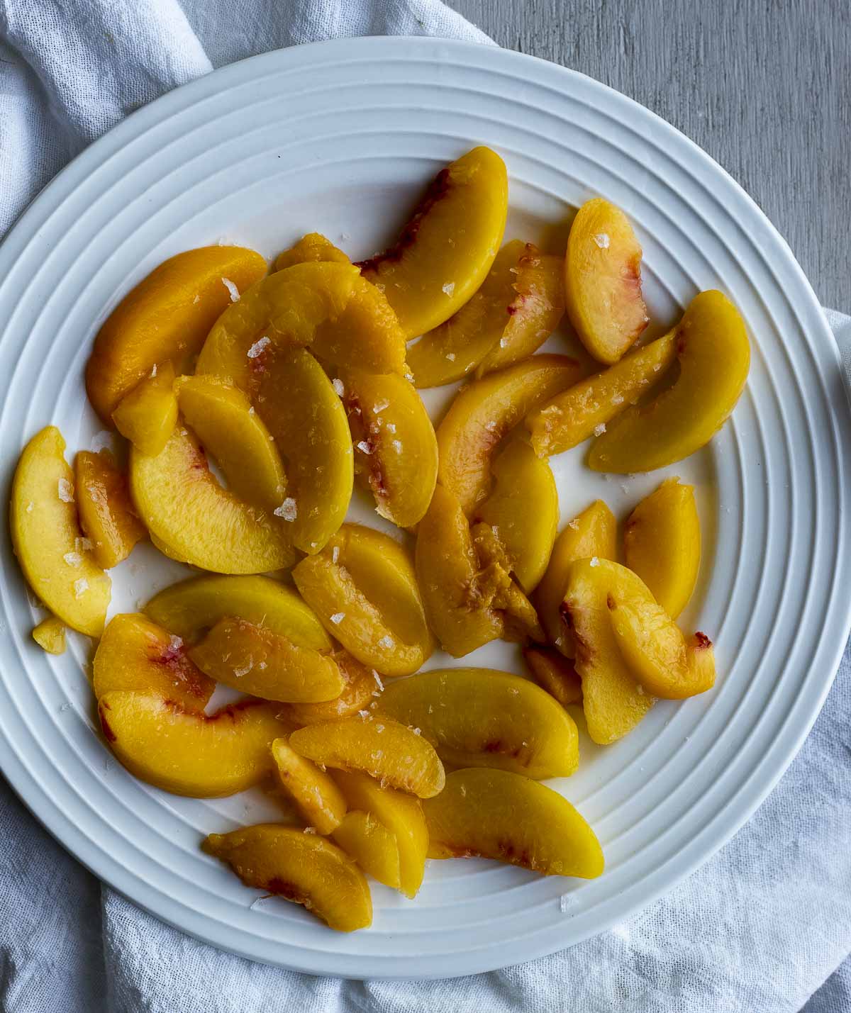 Peach slices on a white plate and sprinkled with sea salt.