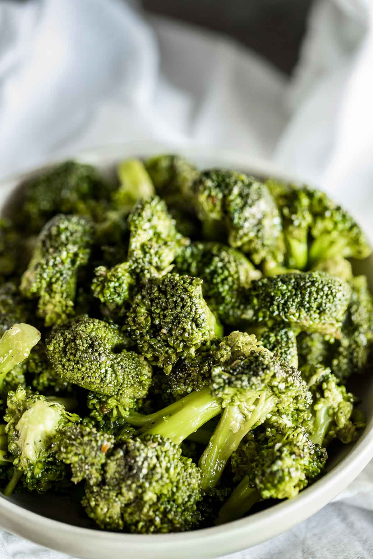 Side view of cooked broccoli florets in a bowl.