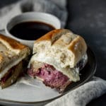 French dip sandwich on a plate with a bowl of jus.