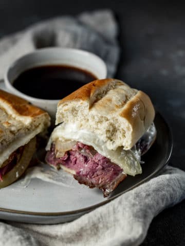 French dip sandwich on a plate with a bowl of jus.