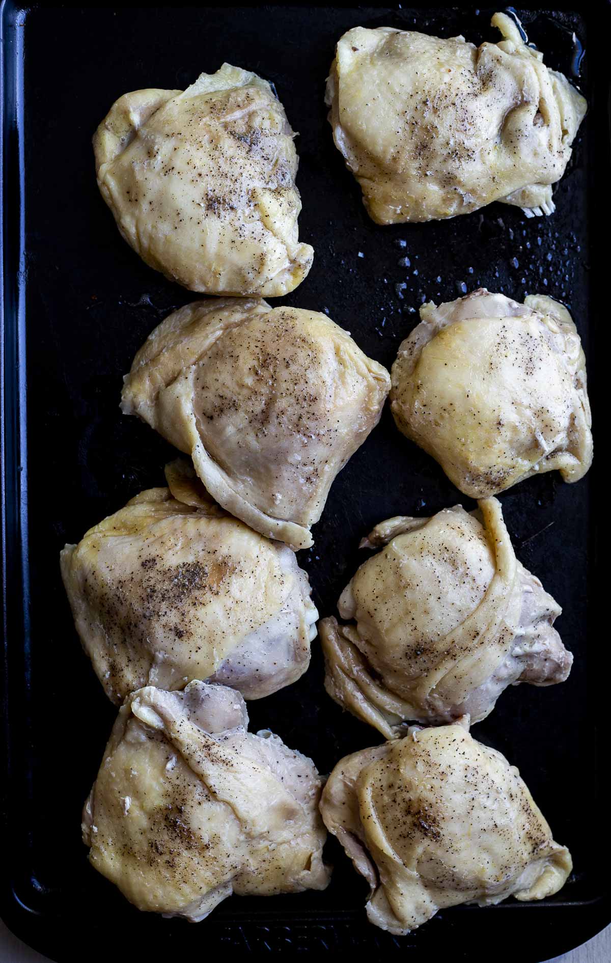 Chicken thighs arranged on a pan.