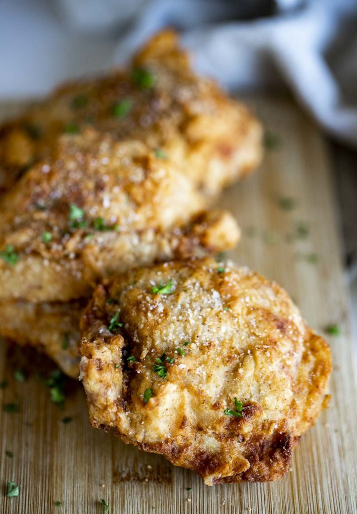 Close up of fried chicken pieces on a wooden board.