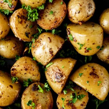 Overhead of mini sous vide potatoes on a plate with herbs sprinkled on top.
