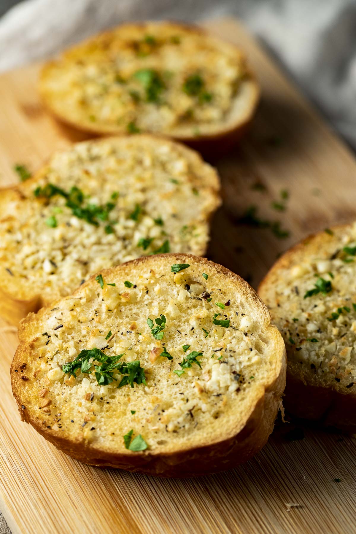 Side view of air fried garlic bread on a wooden board.