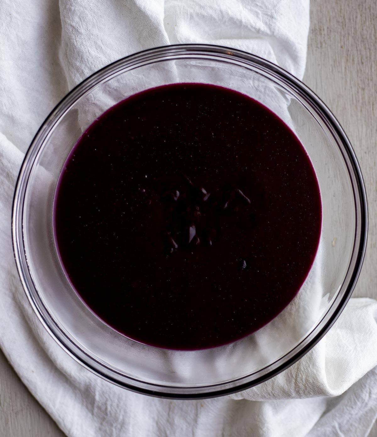 Overhead of blueberry curd in a glass bowl.
