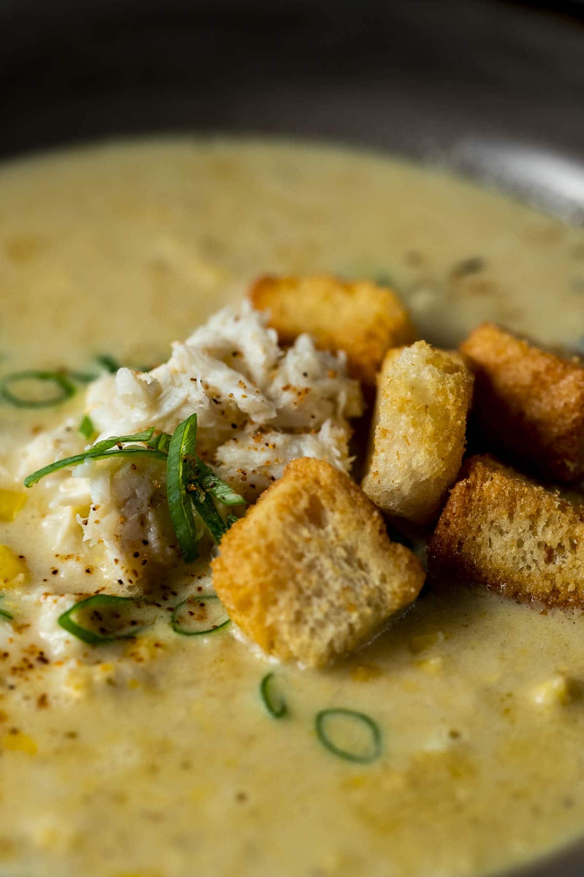 Side close up view of croutons on top of crab and corn bisque.
