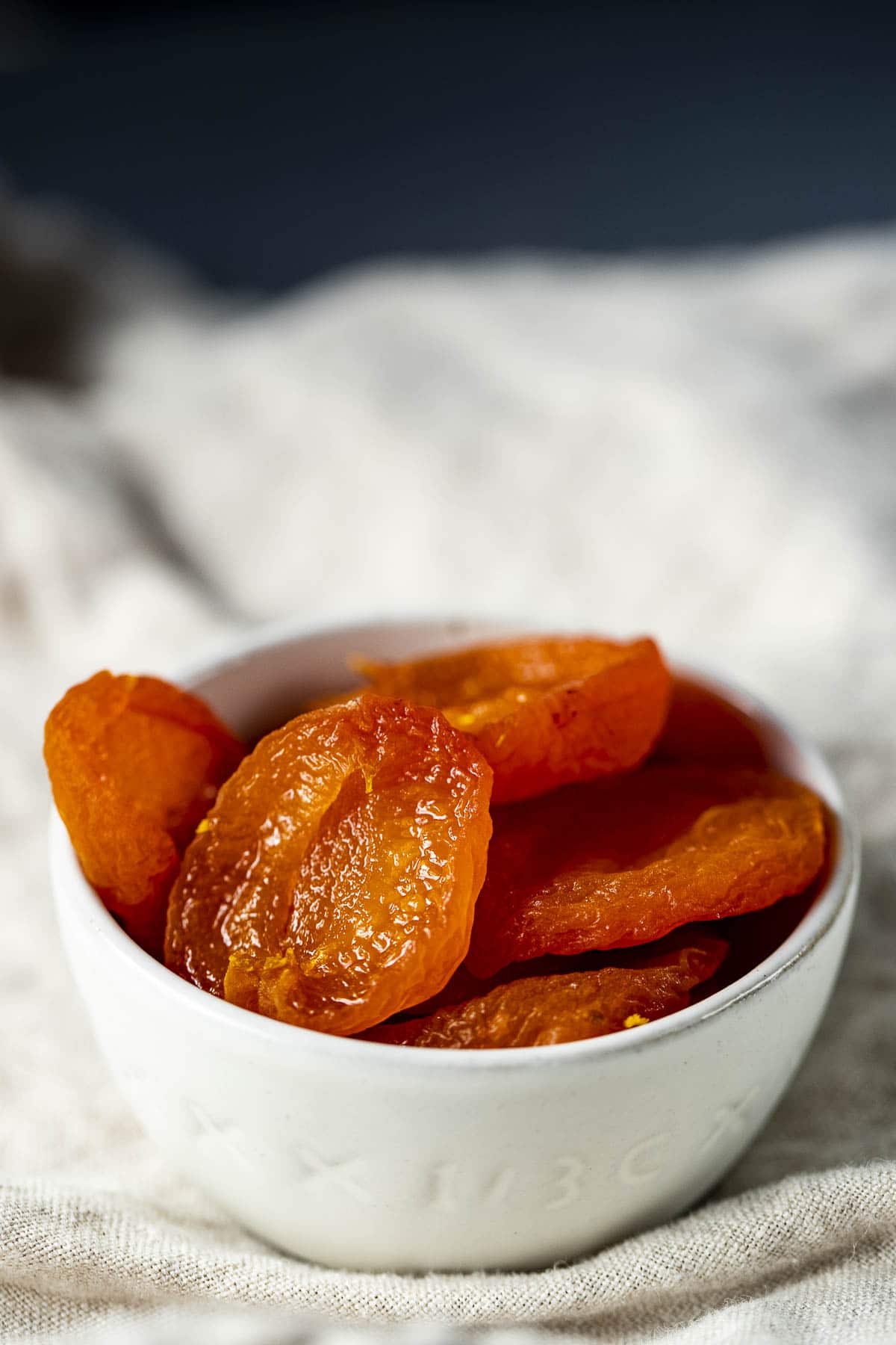 Side view of dehydrated apricots in a white bowl.