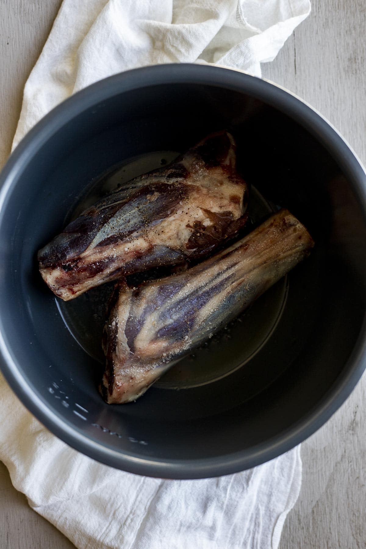 Two lamb shanks being browned in the Instant Pot.