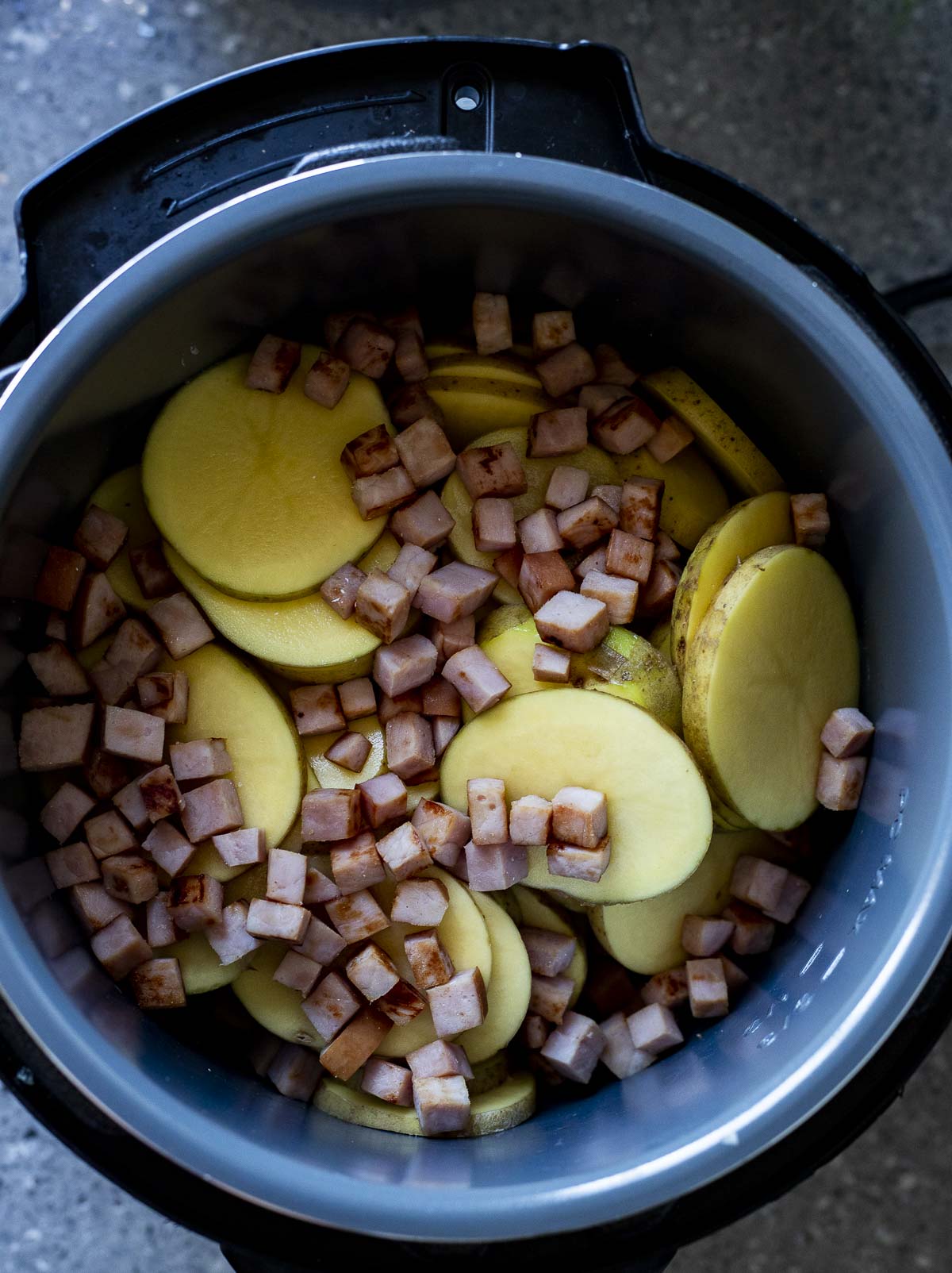 Potato slices and ham added to the Instant Pot.