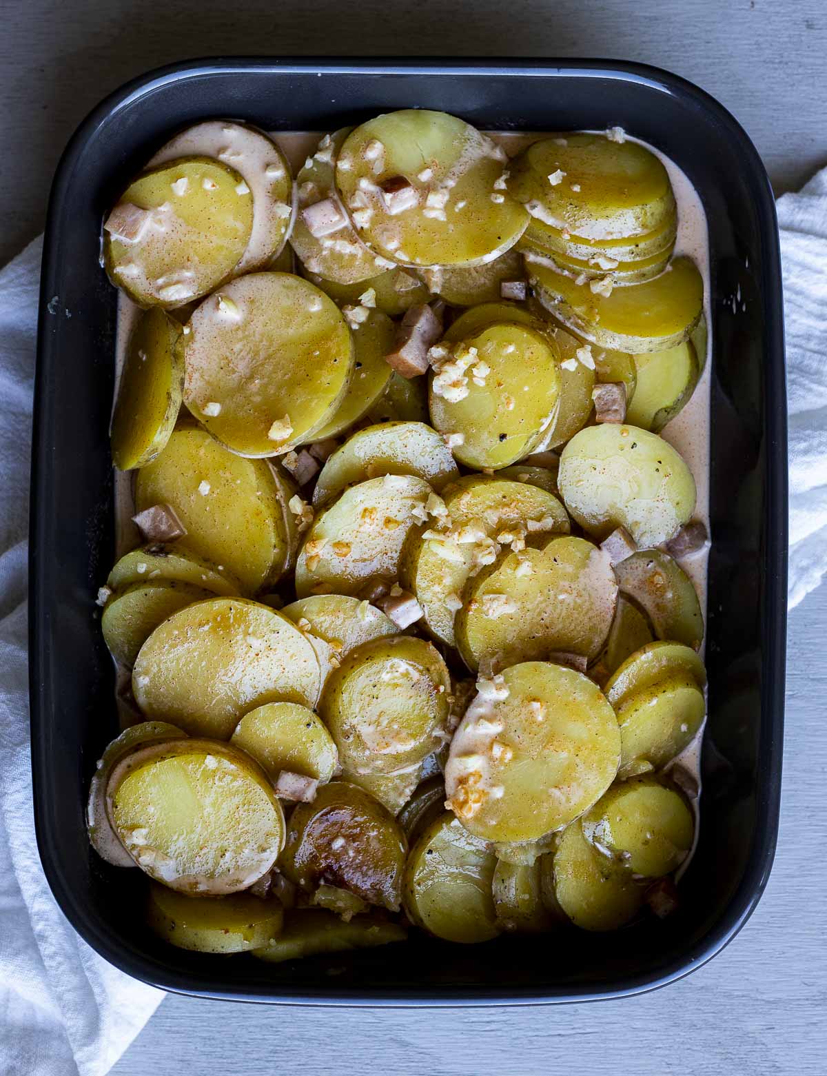 Cooked potato slices arranged in a baking dish.