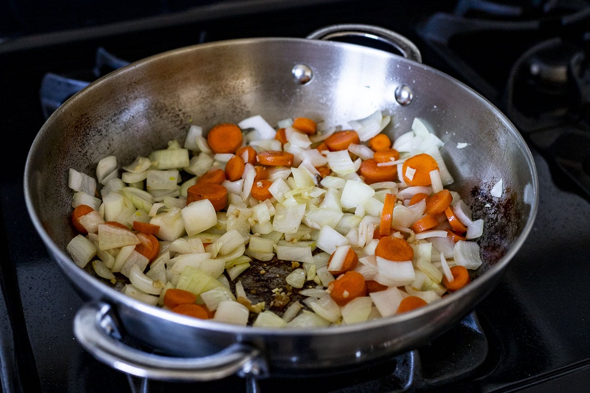 Carrots, onion and garlic cooking in a skillet.