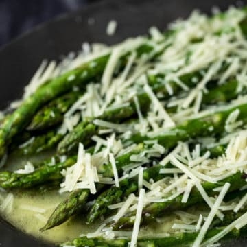 Side view of butter poached asparagus topped with grated parmesan.