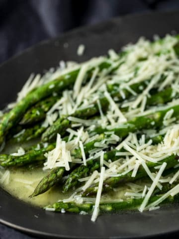 Side view of butter poached asparagus topped with grated parmesan.