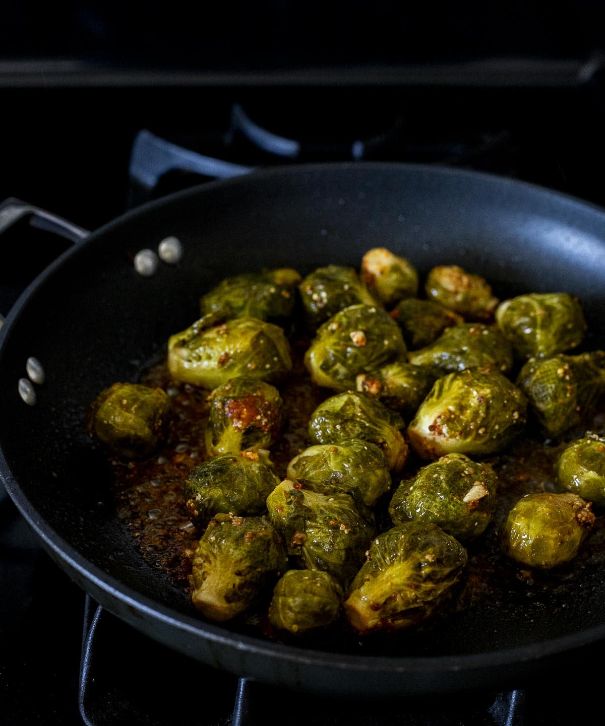 Brussels sprouts being seared in a skillet.