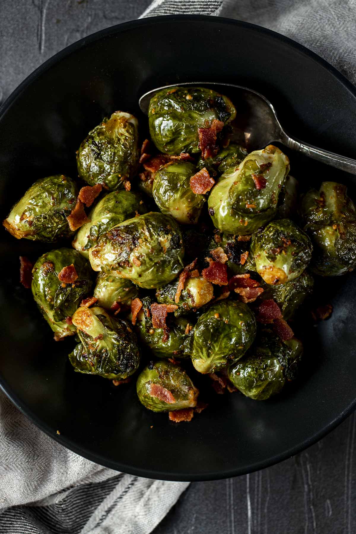 Sous vide Brussels sprouts and bacon served in a black bowl.