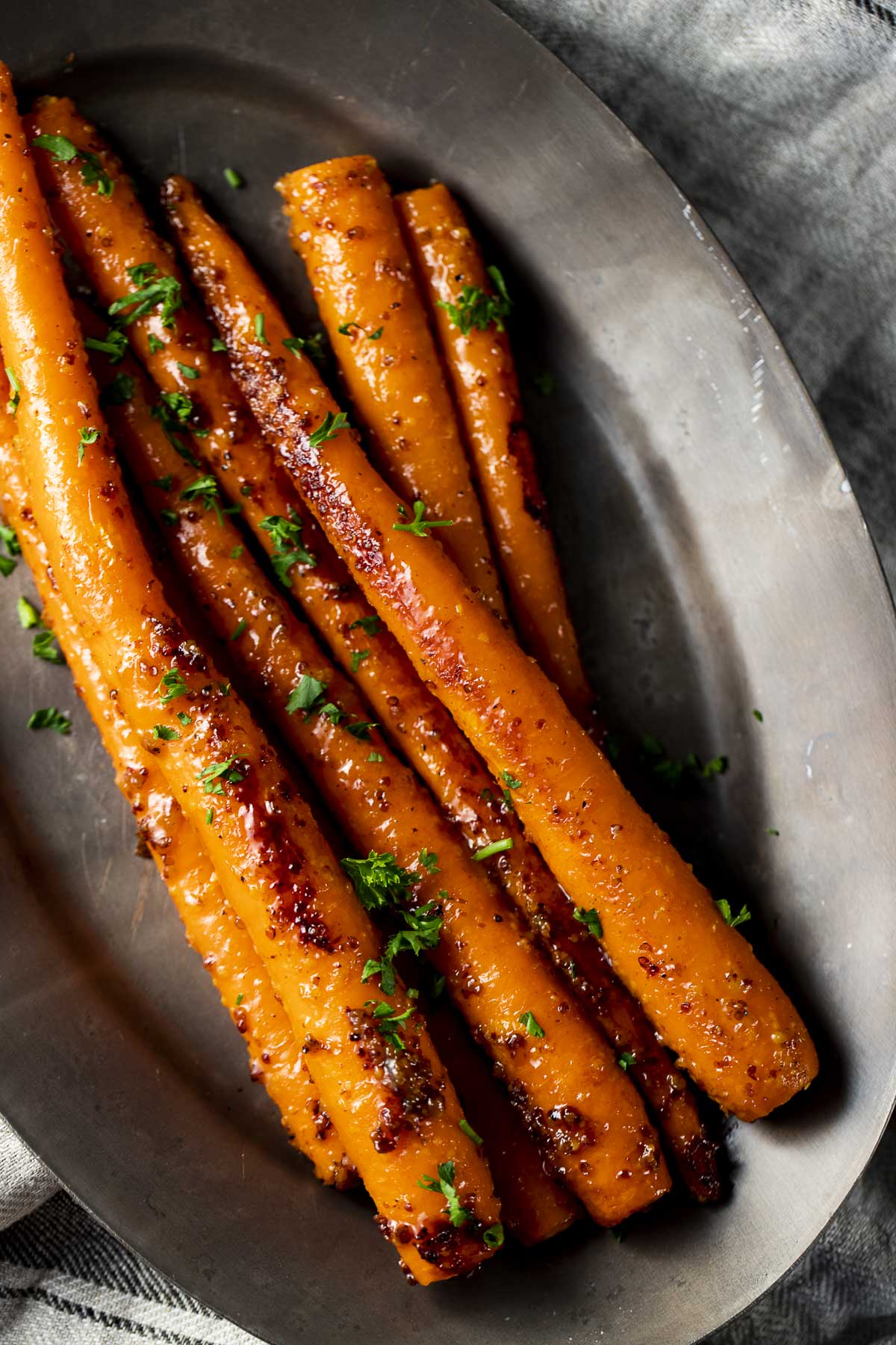 Overhead view of sous vide whole carrots with glaze on a serving tray.