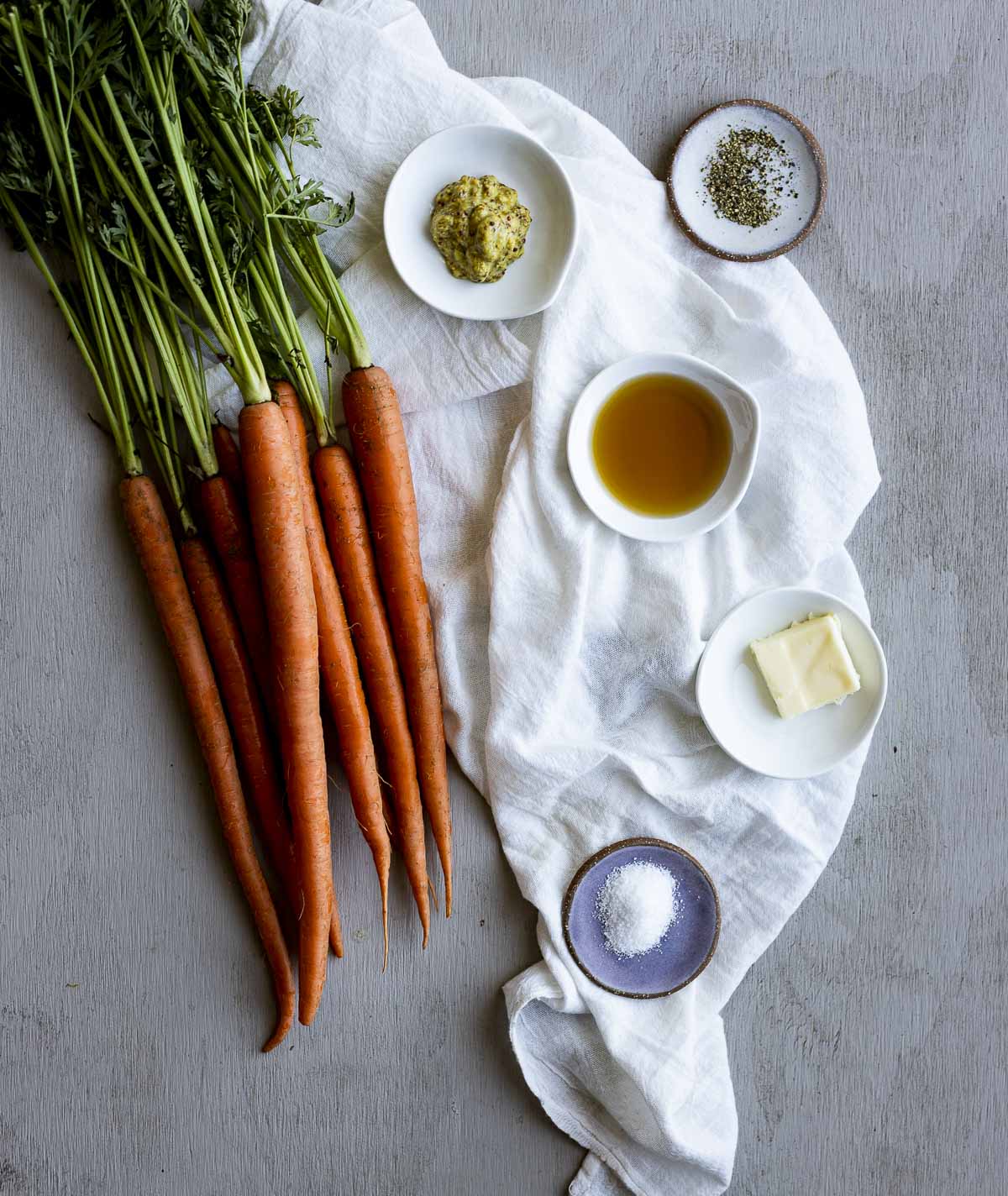 Ingredients to make sous vide carrots arranged individually on a white cloth.