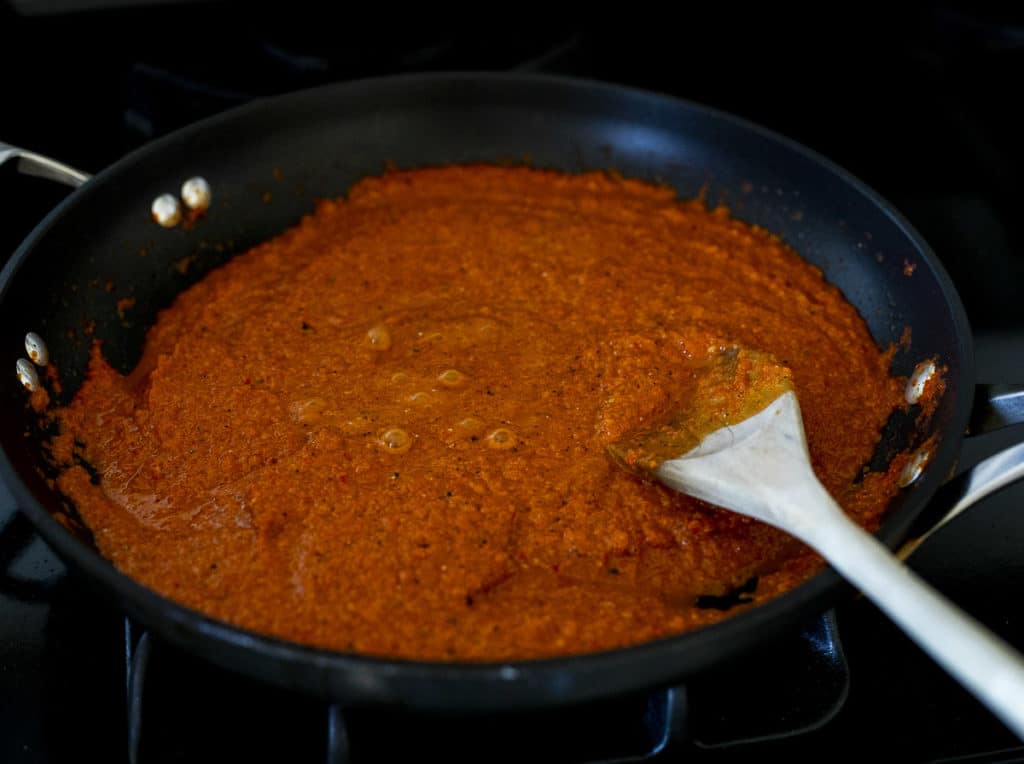 red sauce in a skillet with a wooden spoon