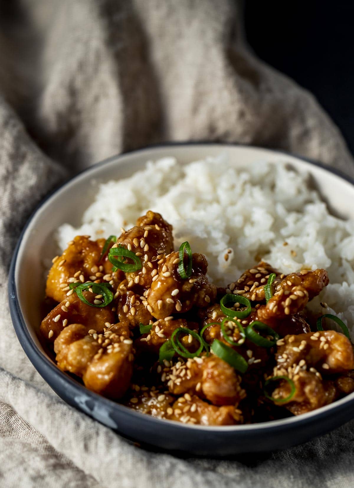 Orange chicken and white rice in a bowl.