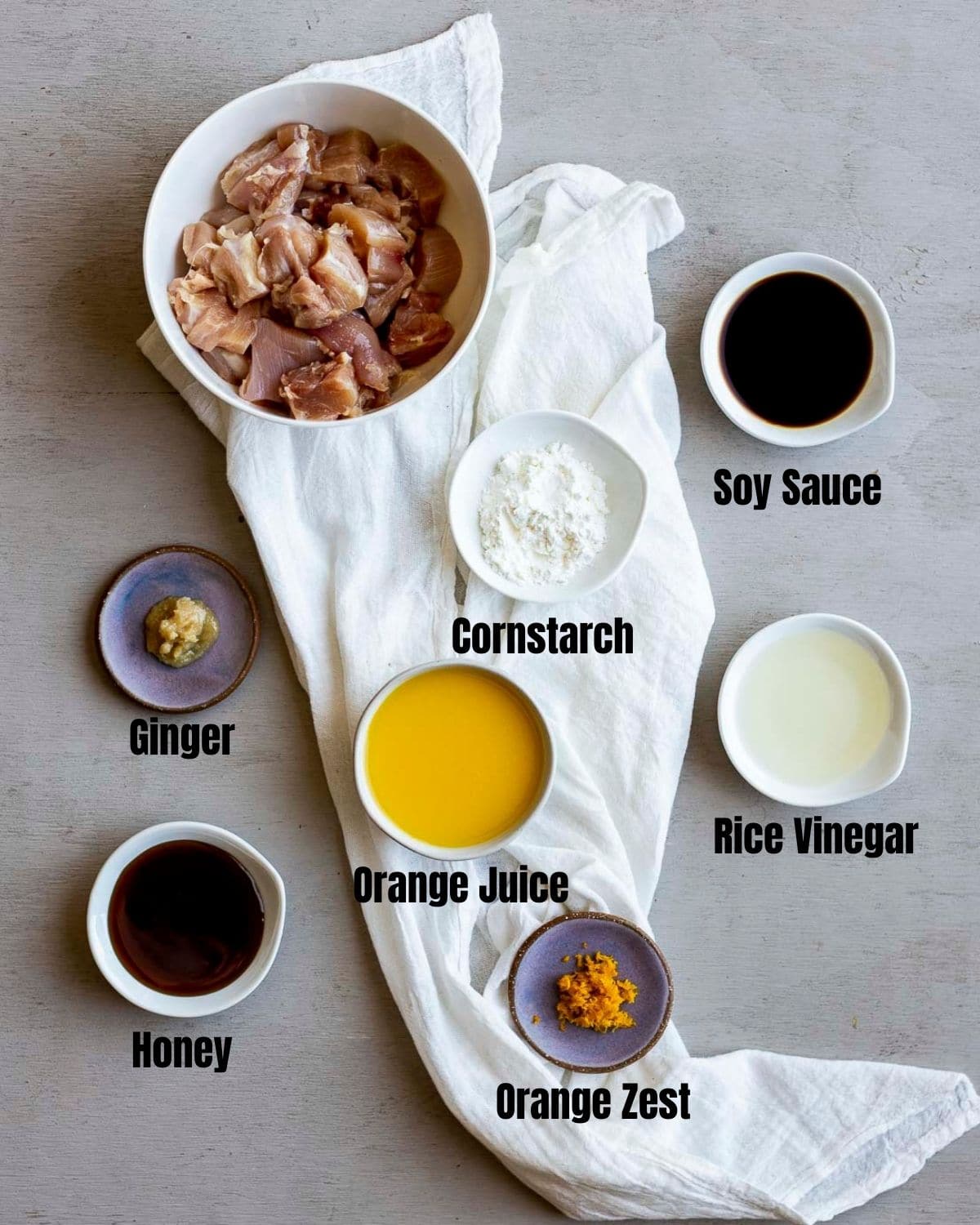 Ingredients to make air fryer orange chicken arranged individually and labelled.