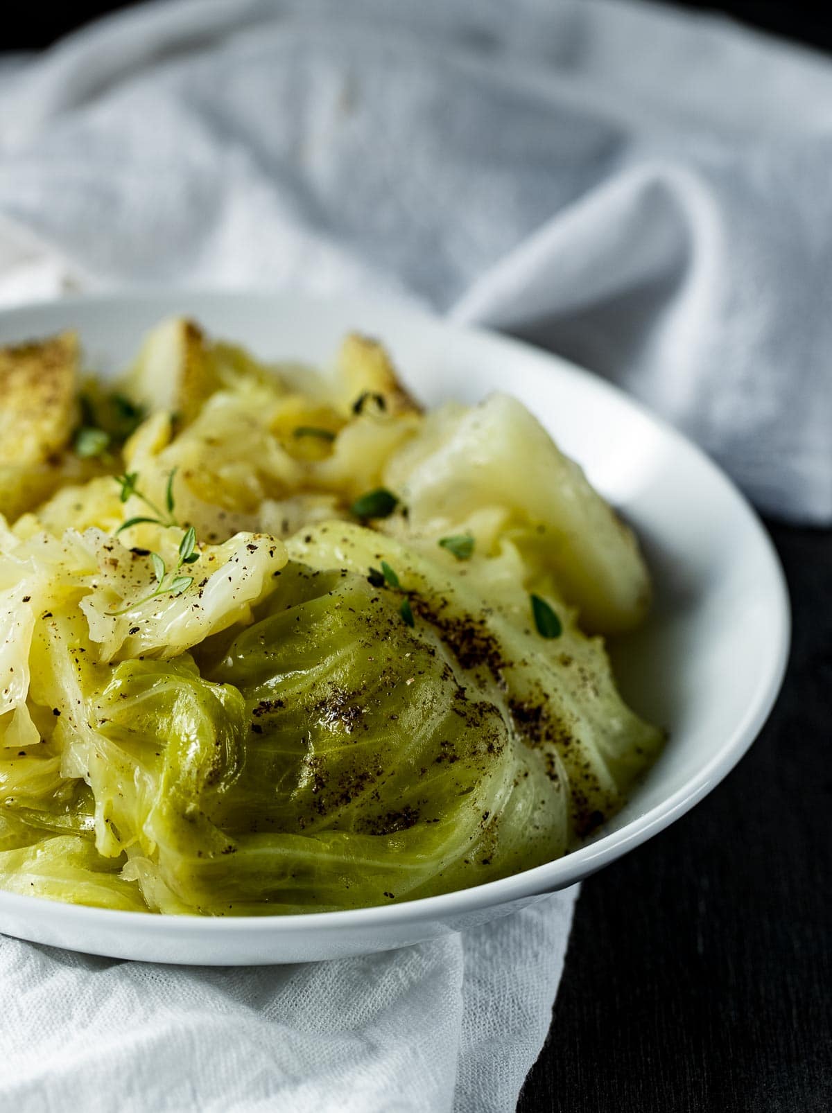 Side view of cooked cabbage in a white bowl.