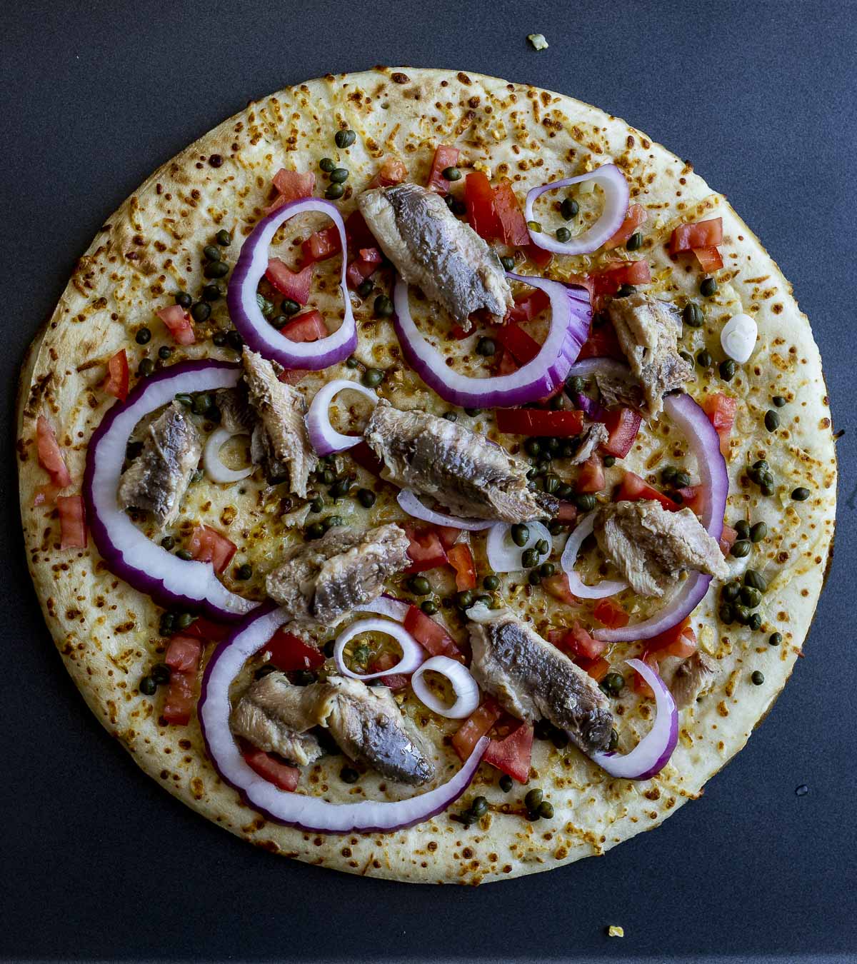 Sardines arranged on top of the pizza.