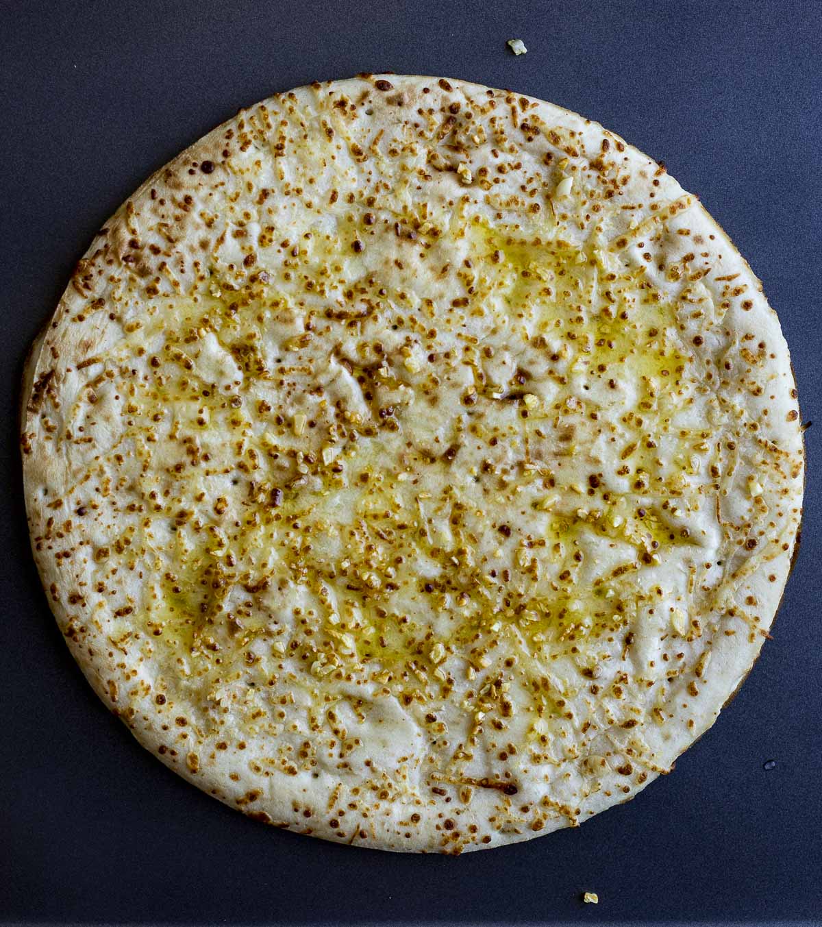 Pre-made pizza crust with garlic olive oil brushed on top.