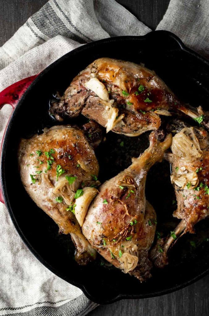 Four duck legs broiled in a cast iron pan.