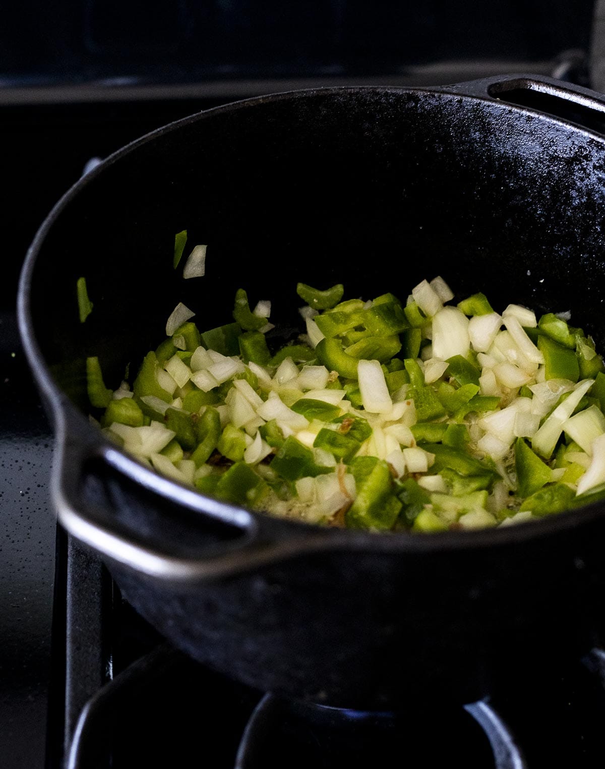 Onion, green pepper and celery cooking in a Dutch oven.