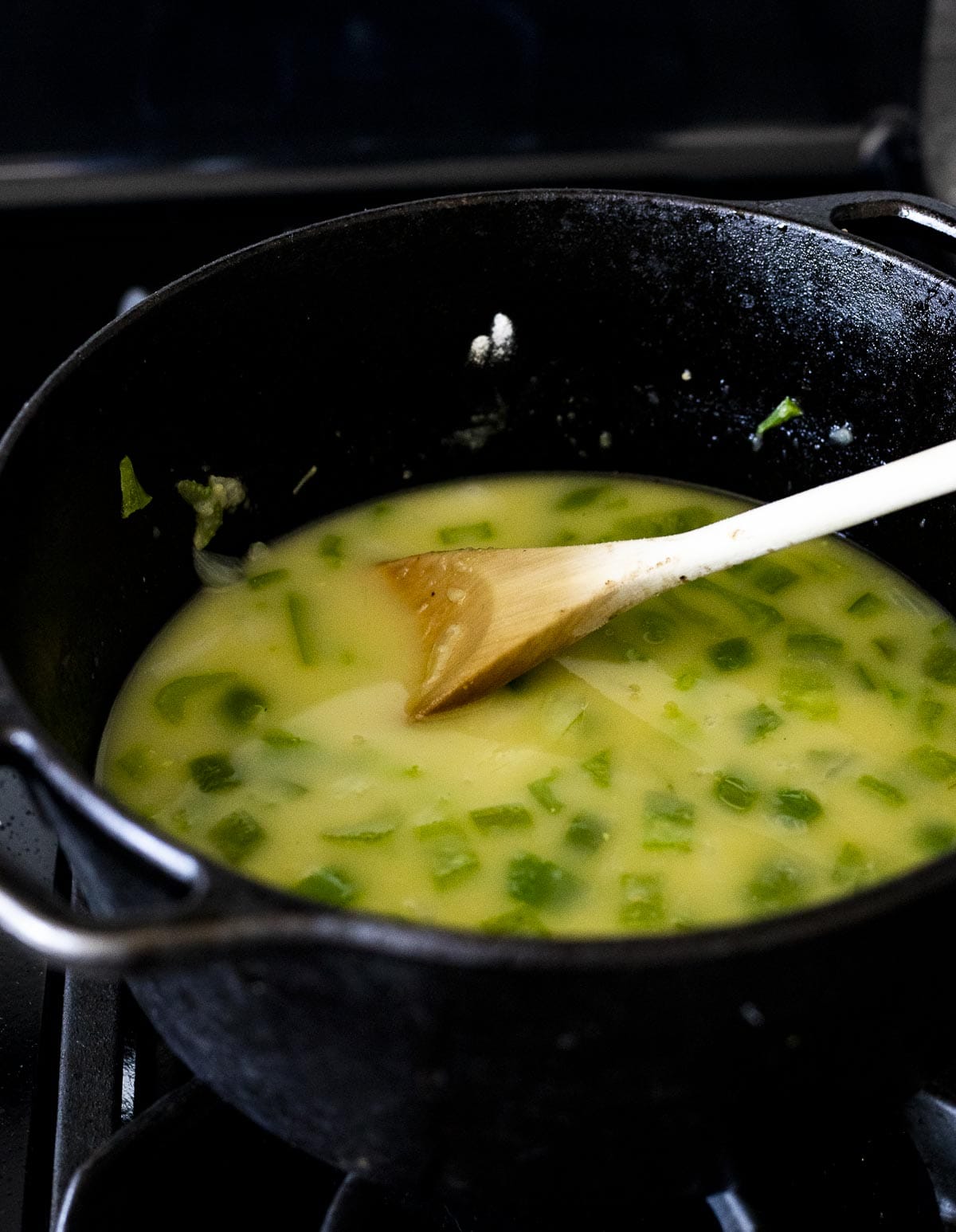 Vegetables and thickened broth being stirred in a pot.