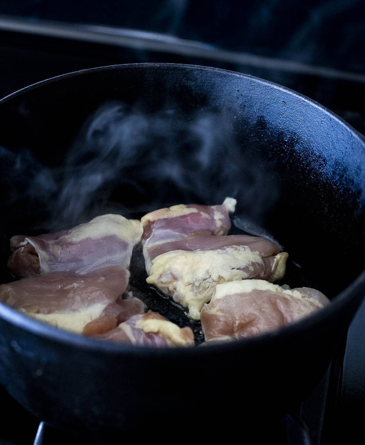 Chicken thighs browning in a Dutch oven.