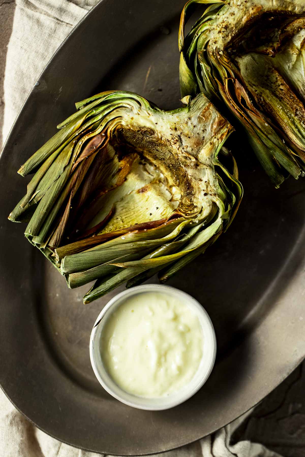 Overhead view of an air fried artichoke half with garlic aioli on the side.