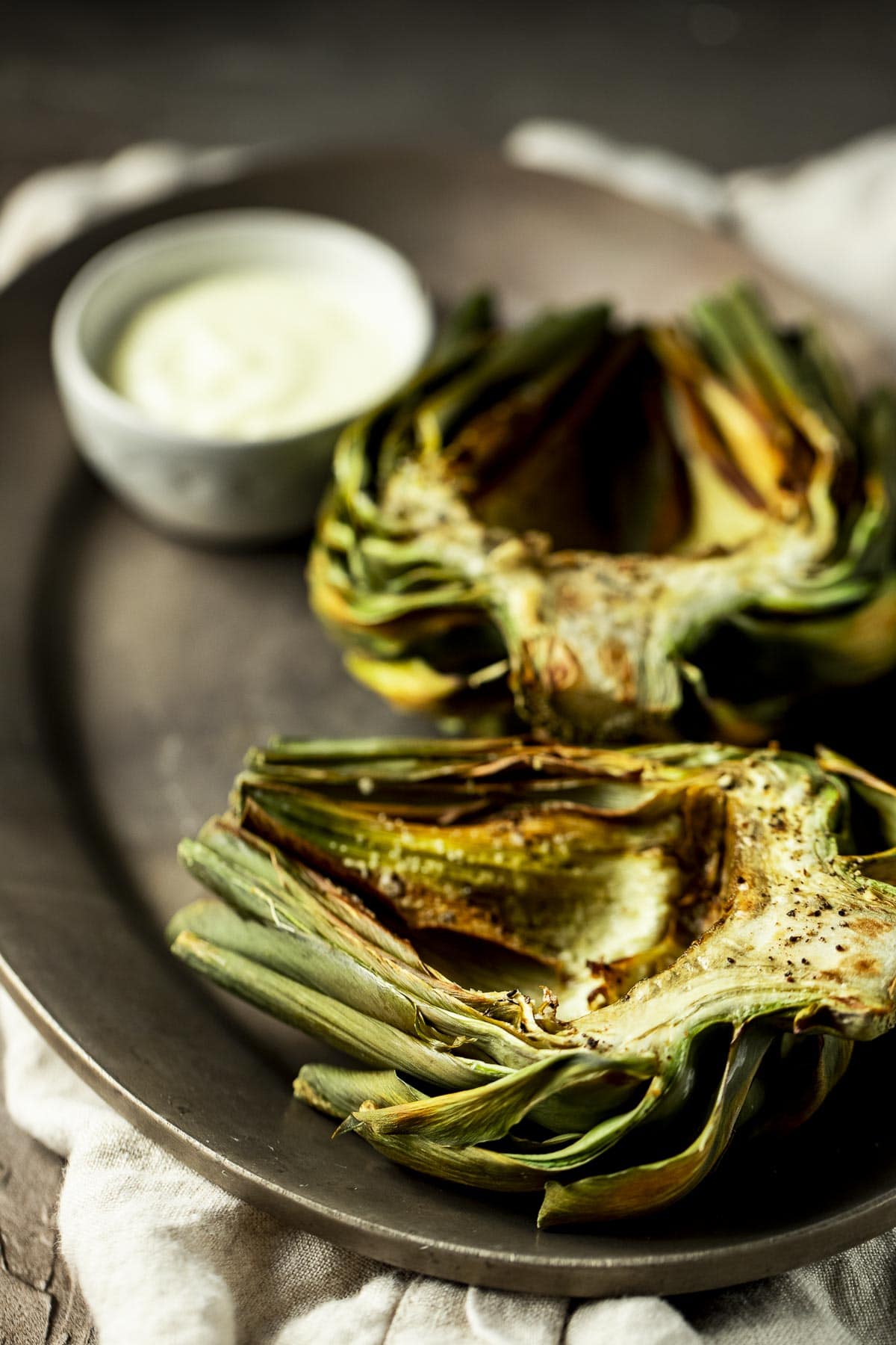Side view of artichoke halves on a plate with garlic aioli.